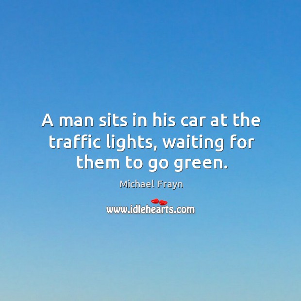 A man sits in his car at the traffic lights, waiting for them to go green. Image