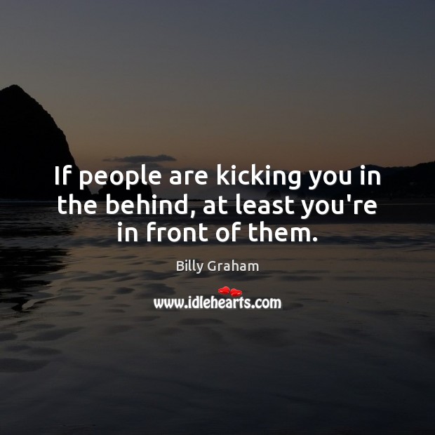 If people are kicking you in the behind, at least you’re in front of them. Billy Graham Picture Quote