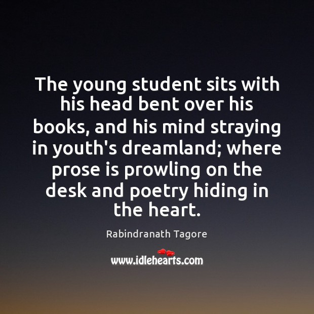 The young student sits with his head bent over his books, and Image